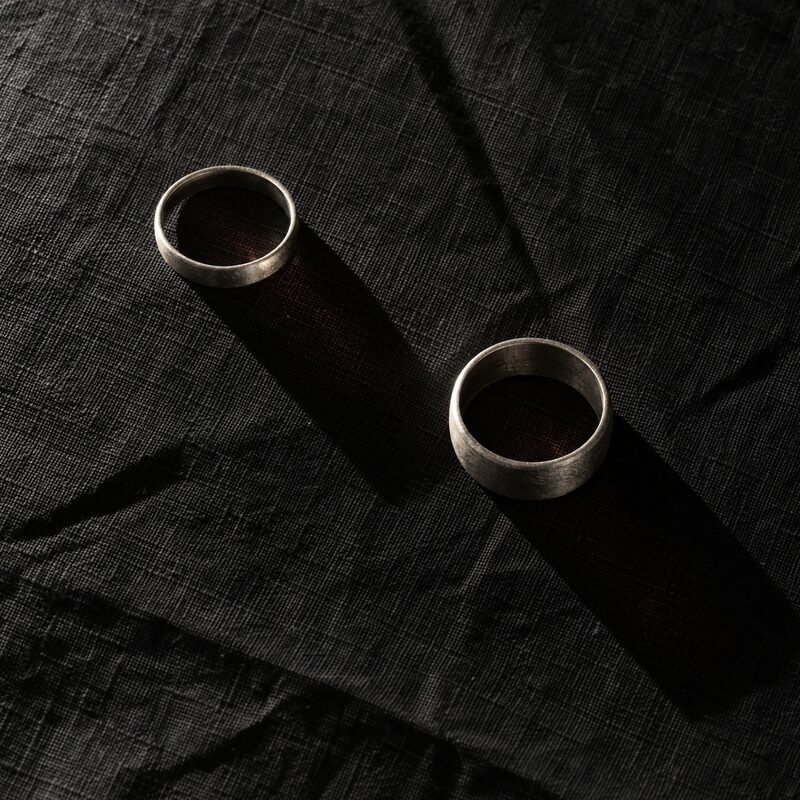 Two rings on dark linen, shot from directly above, hard light.